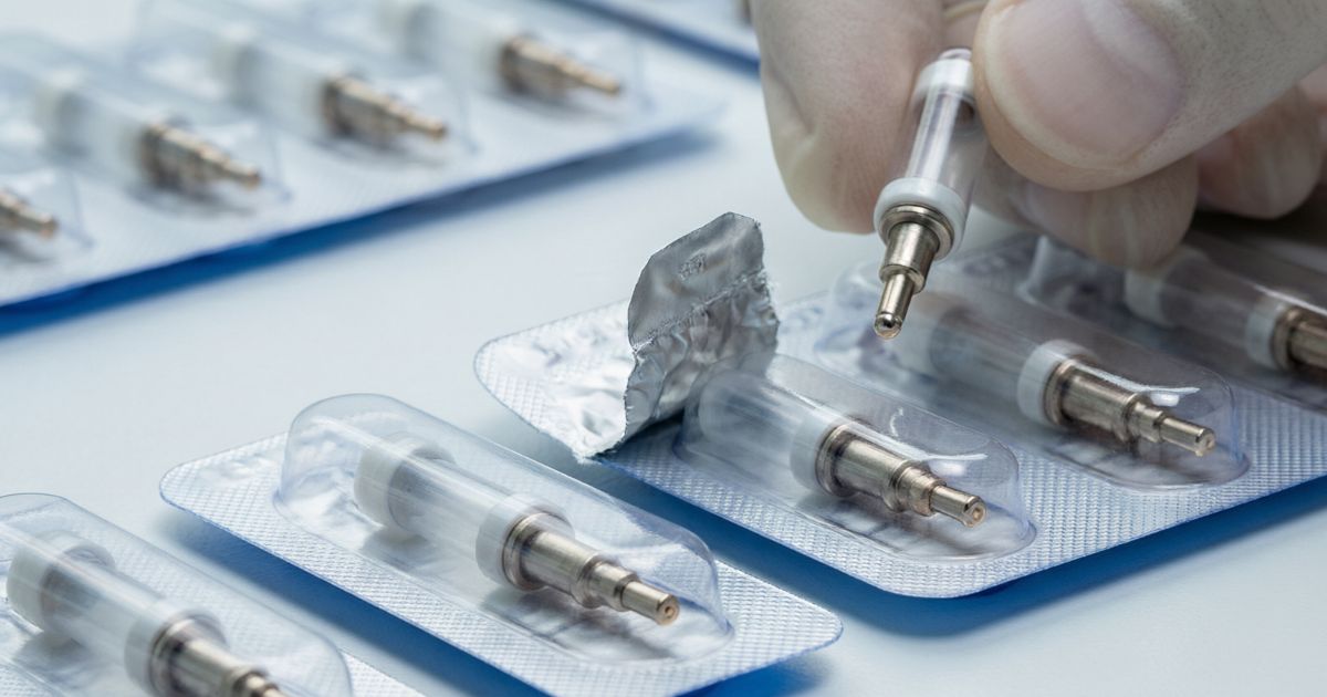 Sealed disposable treatment cartridges in blister packaging, one held up between two fingers